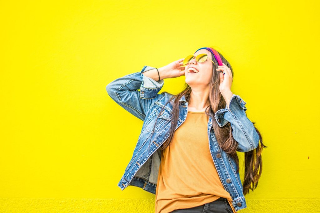 girl laughing in front of yellow wall